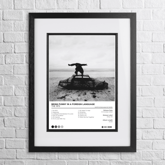 A4 custom design poster of 1975 - Being Funny In A Foreign Language in a black, dual-aspect frame on a white brick background