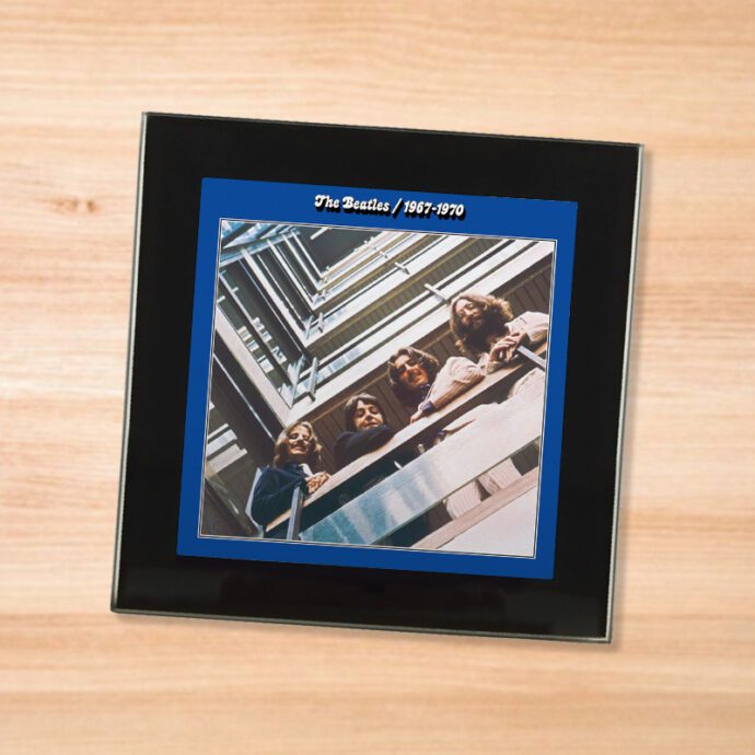 Black glass The Beatles - 1967-1970 coaster on a wood table