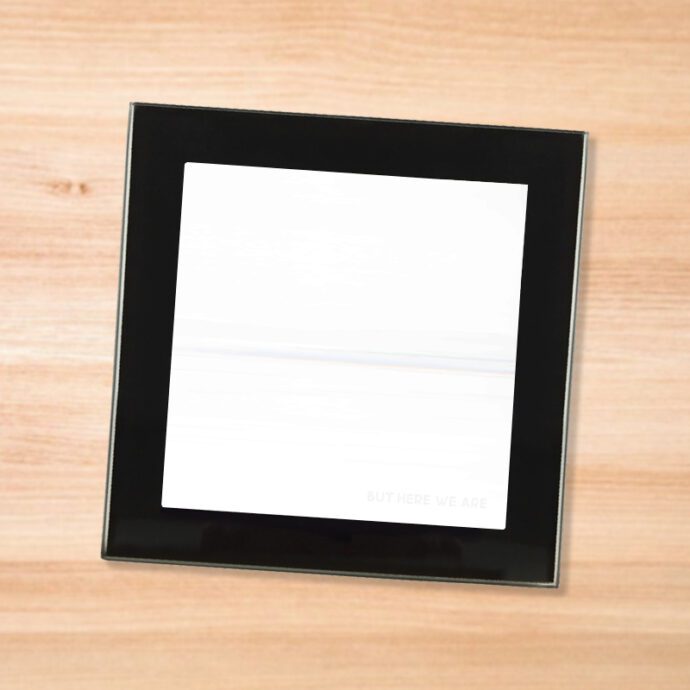 Black glass Foo Fighters - But Here We Are coaster on a wood table