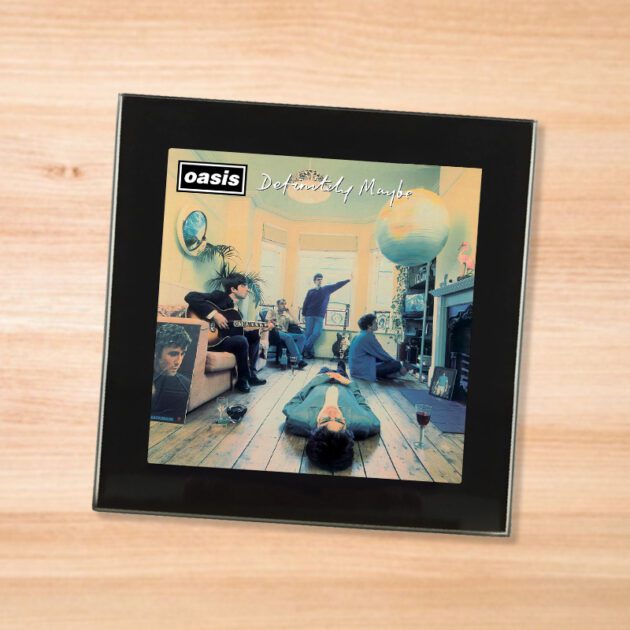 Black glass Oasis - Definitely Maybe coaster on a wood table