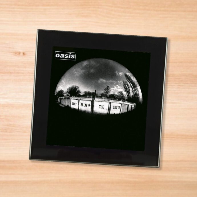 Black glass Oasis - Don't Believe the Truth coaster on a wood table