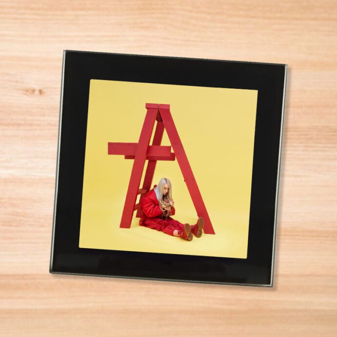 Black glass Billie Eilish - Don't Smile At Me coaster on a wood table