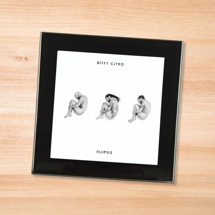 Black glass Biffy Clyro - Ellipsis coaster on a wood table