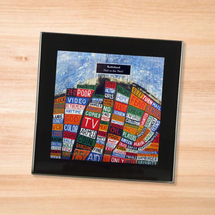 Black glass Radiohead - Hail to the Thief coaster on a wood table