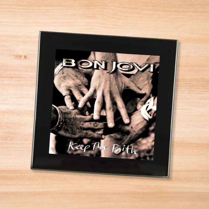 Black glass Bon Jovi - Keep the Faith coaster on a wood table