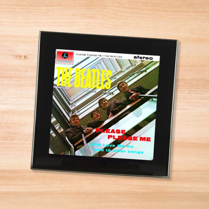 Black glass The Beatles - Please Please Me coaster on a wood table