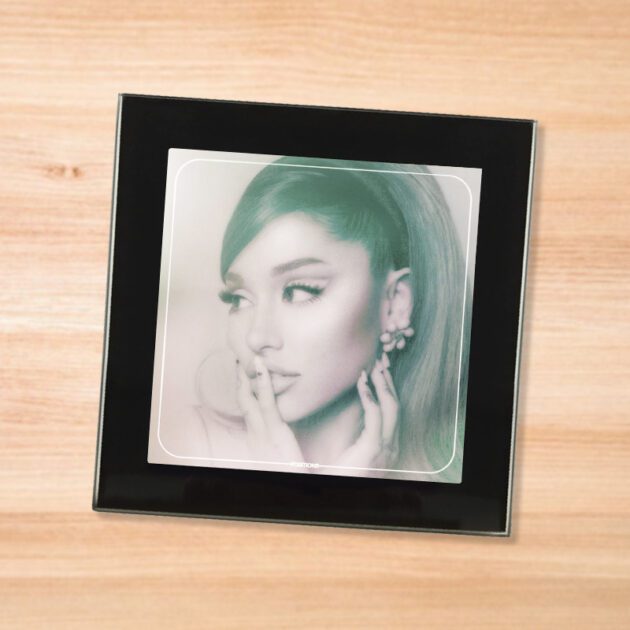 Black glass Ariana Grande - Positions coaster on a wood table