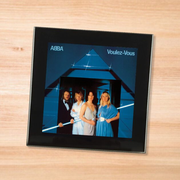 Black glass ABBA - Voulez-Vous coaster on a wood table