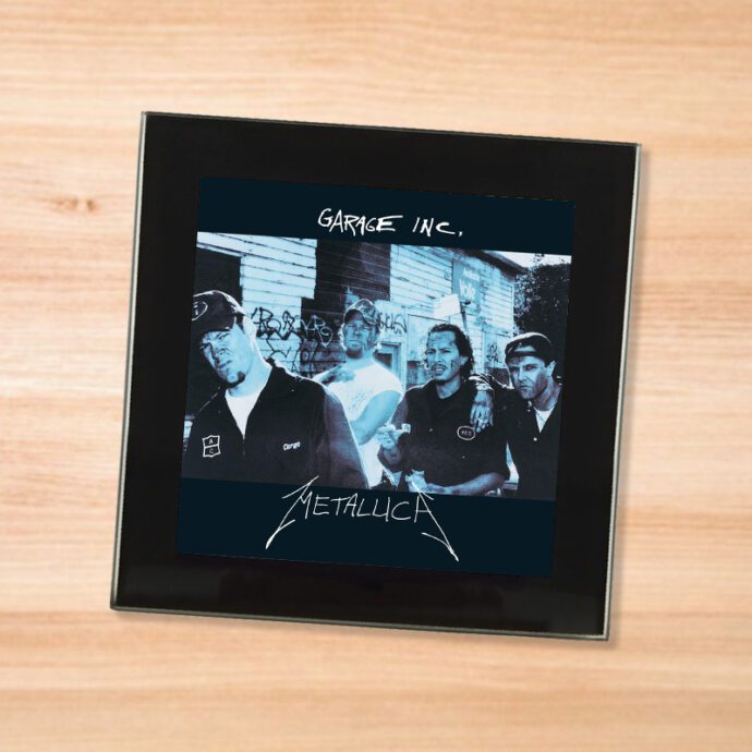 Black glass Metallica - Garage Inc coaster on a wood table