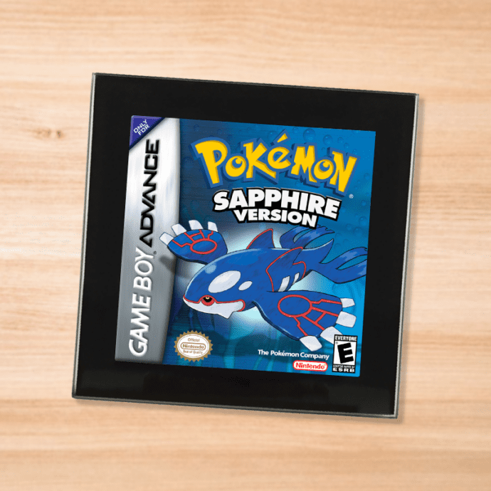 Pokemon Sapphire black glass coaster on a wood table