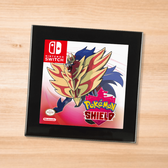 Pokemon Shield black glass coaster on a wood table
