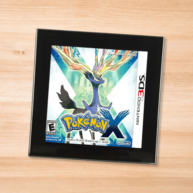 Pokemon X black glass coaster on a wood table